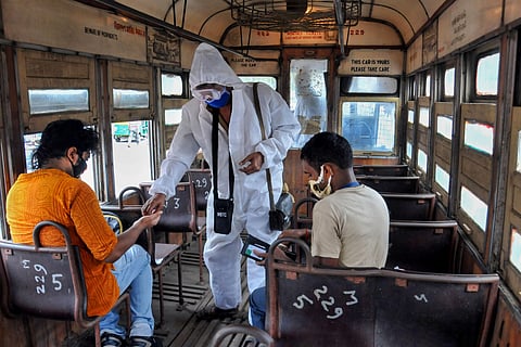 A tram conductor wearing a protective suit takes tickets from passengers after the authorities permitted to resume tram services with certain restrictions during the fifth phase of COVID-19 nationwide lockdown in Kolkata Sunday June 14 2020. (Photo | PTI)