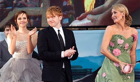 British author JK Rowling, right, looks on as actors, left, Emma Watson and Rupert Grint, applaud the crowd. (File | AP)