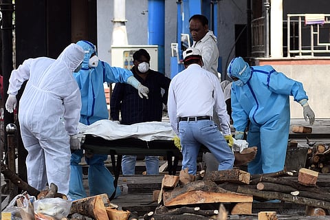 Health workers and family members in personal protective suits move the body of a man who died of Covid 19 for cremation. (File Photo | Parveen Negi, EPS)