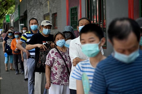 People wearing face masks queue to take a swab test during mass testing for the COVID-19 coronavirus in Beijing. (Photo | AFP)