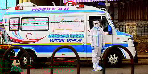 An ambulance driver wearing PPE waits near Kempegowda Bus Station in Bengaluru on Sunday. (Photo| Pandarinath B, EPS)
