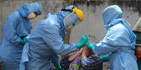 Health workers in PPE suits take the swab sample of a person. (File | PTI)