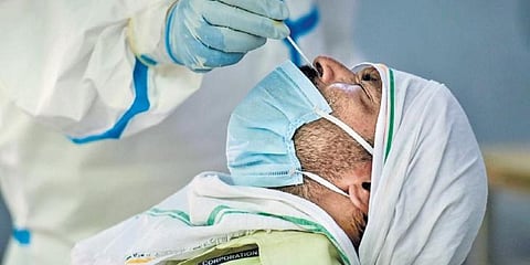 A medic collects a swab sample for COVID-19 from a man at a testing centre. (Photo | PTI)