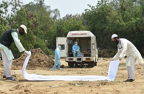 Samim and a family member of a deceased COVID-19 patient prepare for the burial at a graveyard in New Delhi Wednesday April 29 2020. (Photo | PTI)