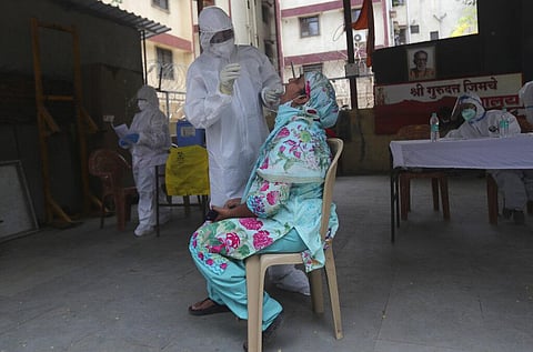 A health worker takes a swab test of a woman during a free medical checkup in Dharavi, one of Asia's biggest slums, in Mumbai. (Photo | AP)