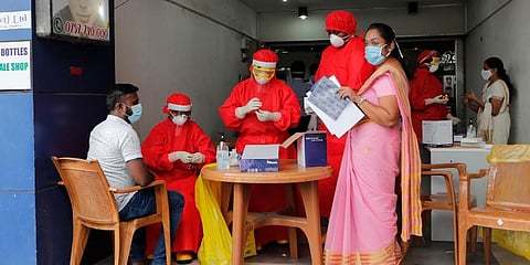 Sri Lankan municipal health workers take a blood sample from a man during screening for COVID- 19 antibodies at a market place in Colombo. (Photo| AP)