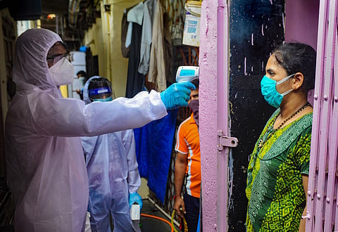A medic checks the temperature of a woman during door-to-door COVID-19 testing at a slum in Mumbai Sunday June 28 2020. (Photo | PTI)