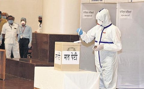 A Congress MLA, who tested Covid positive, casts his vote in PPE for RS election at MP Assembly (File photo | PTI)