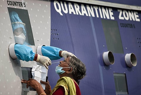 A healthcare worker collects a swab sample of a passenger returning to Vijayawada by Konark Express train, from a mobile swab collection bus at Vijayawada Railway Station, during the ongoing COVID-19 lockdown. (Photo | PTI)