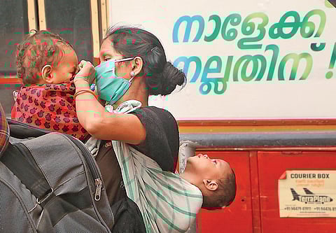 File photot of a woman covering her toddler’s face after coming out of a KSRTC bus on Kozhikode railway station premises, before boarding a special train to Jharkhand (Photo | TP Sooraj, EPS)