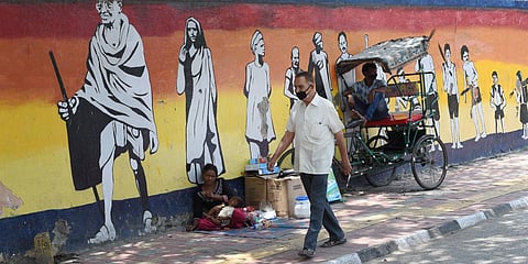 A man wearing a face mask walks past a mural during the ongoing COVID-19 lockdown in New Delhi. (File photo| PTI))