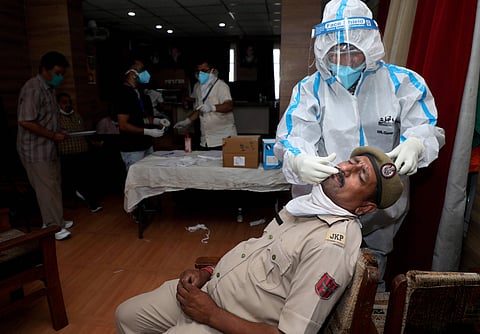 A medic collects swab sample from a policeman for COVID-19 test in Jammu Monday June 29 2020. (Photo | PTI)