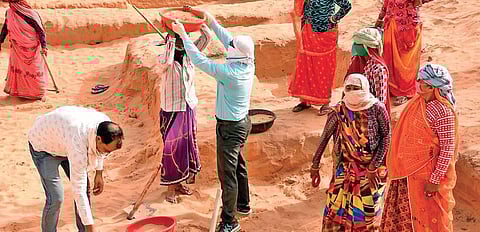 Ramavatar Singh (in blue shirt) helps a woman take away sand dug out from an MGNREGA work site