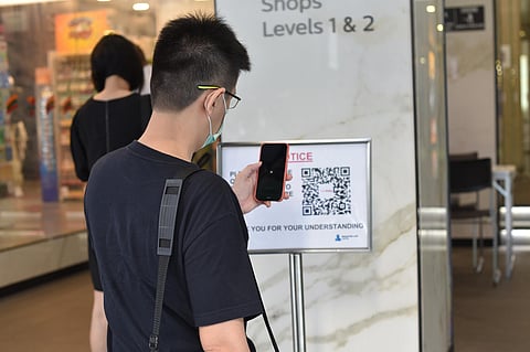 A man scans a QR code before entering a building in Singapore. (Photo | AP)
