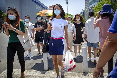 People wear face masks to protect against the coronavirus as they walk across an intersection in Beijing, Friday, June 5, 2020. China on Friday reported five new confirmed coronavirus cases, all of them brought by Chinese citizens from outside the country