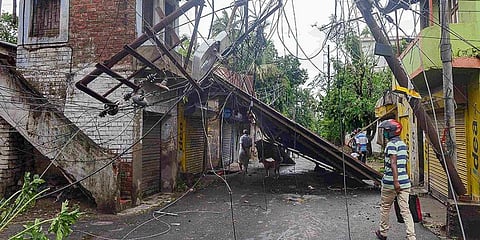 A man walks past a damaged electric post in the aftermath of Cyclone Amphan, at Sonarpur in South 24 Parganas district. (Photo | PTI)