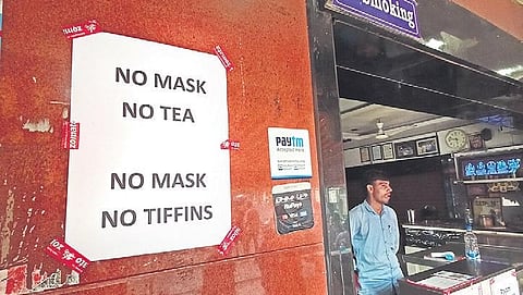 A poster that reads ‘No mask, No tea’ is pasted at the entrance of a restruant as it gets ready to open up on Monday | RVK Rao