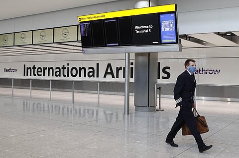 A pilot wears a facemask as he arrives at Terminal 5 at Heathrow airport. (Photo| AFP)