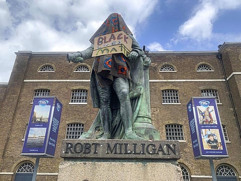 The statue of Robert Milligan, a noted West Indian merchant, slaveholder and founder of London's global trade hub, West India Docks, stands covered in a sack-cloth and sign reading Black Lives Matter, outside the Museum of London Docklands. The recent dea