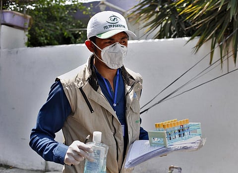A health worker leaves after collecting samples from a family for coronavirus testing at a neighborhood in Islamabad, Pakistan. (Photo | PTI)