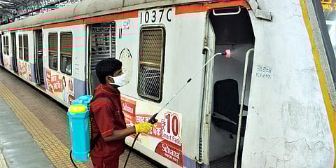 A worker sprays disinfectant to sanitize the motor man's cabin of a local train, at Chhatrapati Shivaji Maharaj Terminus in Mumbai. (File photo| ANI)