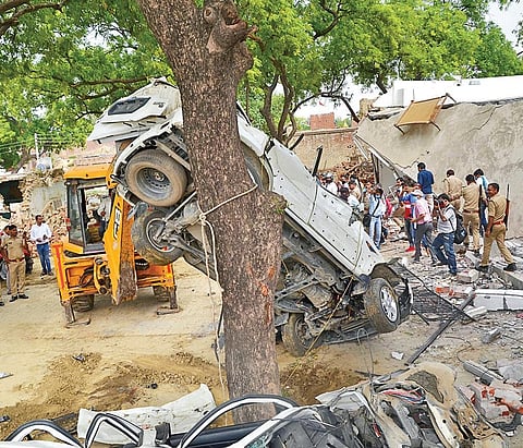 An earthmover removes mangled remains of a SUV during the demolition of the residence of gangster Vikas Dubey in Bikru village (File photo | PTI)