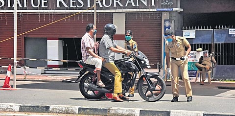 A policeman on a two-wheeler with a pillion rider breaks a rope tied across the street at Statue Junction in lockdown-imposed Thiruvananthapuram on Sunday. Since the rider was a policeman, he was allowed to go without any hassle | B P DEEPU