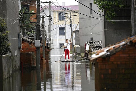 A woman pushes a makeshift raft down a flooded alleyway in a village in Yongxiu in central eastern China's Jiangxi province. (Photo | AP)