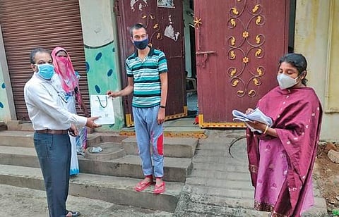 GHMC officials hand over a home isolation kit to a Covid-19 patient at Yosufguda in Hyderabad on Thursday. (Photo| EPS)