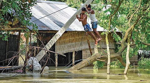 Villagers try to fix an uprooted electric pole at a flood-affected village in Assam’s Morigaon district on Friday | Pti