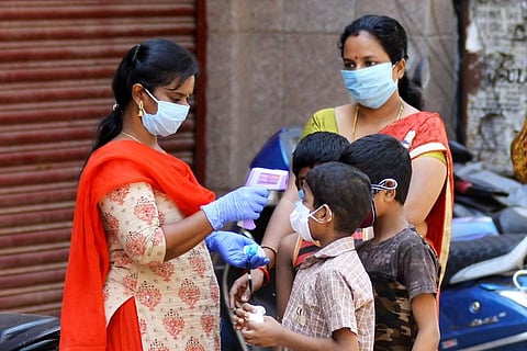 A healthcare worker checks temperature of kids at a fever camp organized by GCC at a street near Mint in Chennai. (Photo | Debdatta Mallick, EPS)