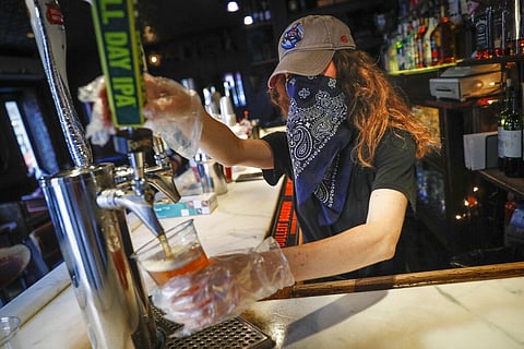 In this June 22, 2020, file photo, a bartender pours a beer for a customer at Shade Bar NYC in New York. Authorities are closing honky tonks, bars and other drinking establishments in some parts of the U.S. to stem the surge of COVID-19 infections — a mov