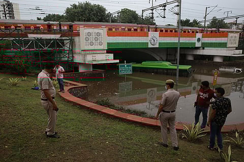Police personnel near the body of a tempo driver who died due to drowning of his vehicle at the waterlogged Minto Bridge underpass following incessant rains in New Delhi. (Photo | Shekhar Yadav, EPS)