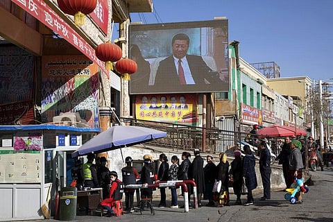 In this Nov. 3, 2017, file photo, residents line up at a security checkpoint into the Hotan Bazaar where a screen shows Chinese President Xi Jinping in Hotan in western China's Xinjiang region. (Photo | AFP)