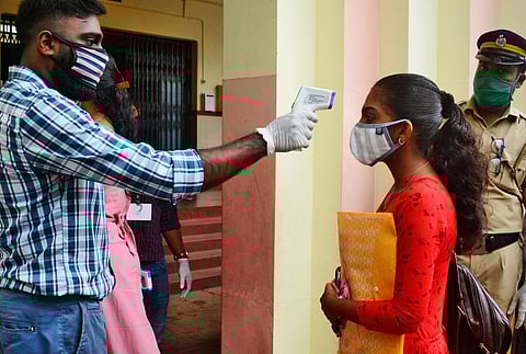 (For representational purposes) Officials checking the body temperature of the students arriving at the KEAM 2020 exam centre in Kozhikode. (Photo | EPS)