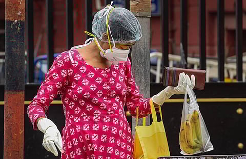 A woman wearing a face mask and gloves looks in her bag during Unlock 2.0 in Kolkata Sunday July 19 2020. (Photo | PTI)