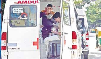 Ambulance staffers on Covid-19 duty grab a bite as they wait near a testing centre on JC Road, Bengaluru, on Tuesday | Nagaraja Gadekal