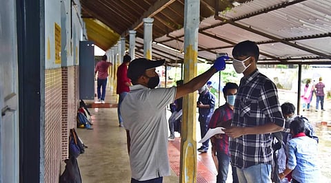 A staff using thermal scanner on a student who came to appear for the KEAM examination at Govt HSS Edappally. (Photo | Albin Mathew, EPS)