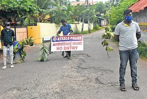 Volunteers of Kerala Sannadha Sena stand guard after blocking the road at Vilayilmoola in Kadakavoor panchayat in Thiruvananthapuram, a coastal area which was declared a critical containment zone till