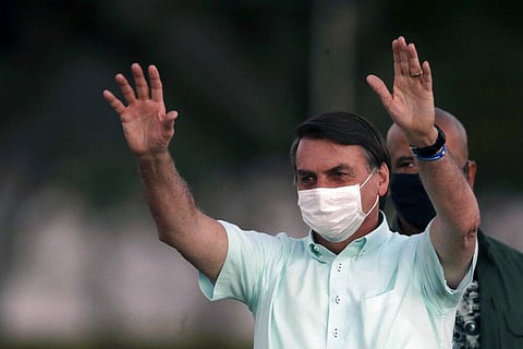 Brazil's President Jair Bolsonaro, who is infected with COVID-19, wears a protective face mask as he greets supporters (Photo | AP)