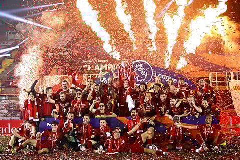 Liverpool's Jordan Henderson holds the English Premier League trophy aloft after it was presented following the Premier League soccer match between Liverpool and Chelsea. (Photo | AP)