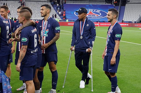 Paris Saint-Germain's French forward Kylian Mbappe (C) walks with crutches after winning the the French Cup final football match. (Photo | AFP)