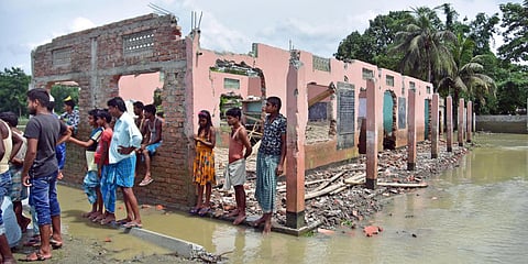 Villagers stand next to part of a school that collapsed due to floodwater at Bhurbandha village near Samaguri inAssam's Nagaon district. (Photo| ANI)