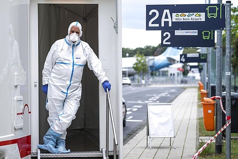 A person in protective clothes stand in the entrance of test station for the coronavirus (Photo| AP)