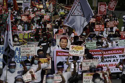 Protesters hold a picture of Philippine President Rodrigo Duterte, center, as they march to protest against the 5th State of the Nation Address of Duterte in Manila. (Photo |AP)