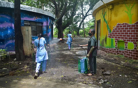A guard sprays disinfectants on a young girl as municipal health workers conduct screening of COVID-19 patients at a children's home in Mumbai Wednesday July 29 2020. (Photo | PTI)