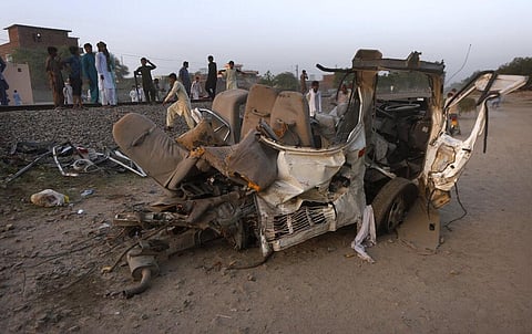 Local residents gather beside the wreckage of a bus close to a railway track following a train and bus accident, in Farooq Abad in Sheikhupura district, Pakistan, Friday, July 3, 2020. (Photo | AP)