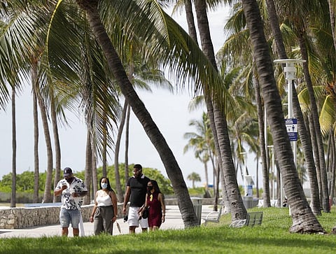A group of people, wearing face masks to prevent the spread of the coronavirus, walk along a beach path on Miami Beach, Florida's famed South Beach, July 4, 2020. (Photo | AP)