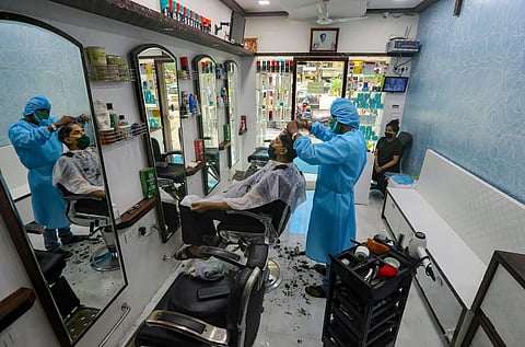 A hair-stylist wearing protective suit attends to a customer at a salon that opened after a gap of three months owing to COVID-19 pandemic at Kandivali in Mumbai. (Photo | PTI)