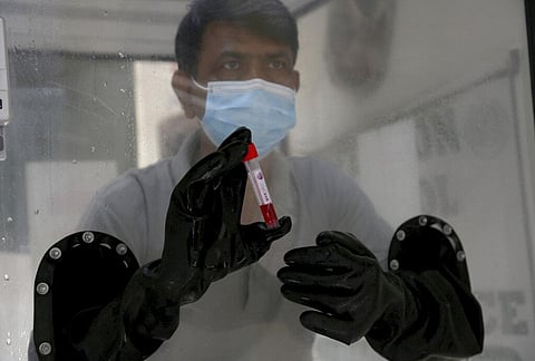 A health worker holds a sample at a testing and screening facility for the new coronavirus, in a hospital in Karachi. (Photo | AP)